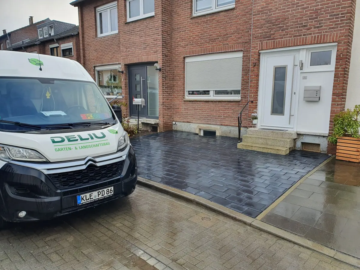 Einsatzfahrzeug von Gartenbau Deliu vor einem Wohnhaus mit neu gestalteter Terrassenanlage