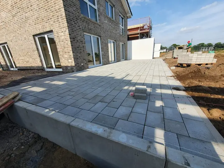 Terrasse aus hellen Großformatplatten im Kontrast zu traditioneller Klinkerfassade
