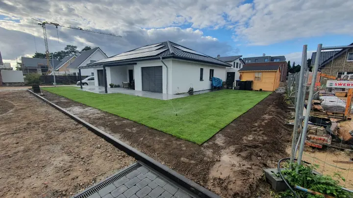 Neu angelegte Rasenfläche mit akkurater Pflasterkante am Wohnhaus