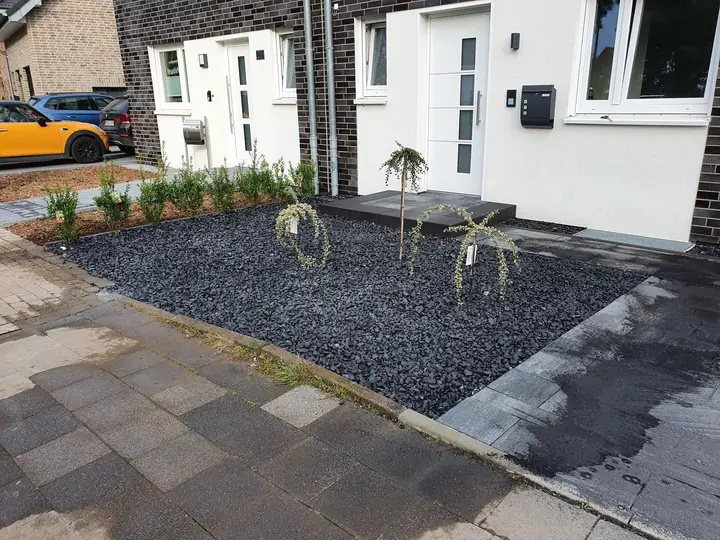 Moderne Terrassenfläche mit dunklem Spritzschutz-Kiesstreifen und sauberer Einfassung