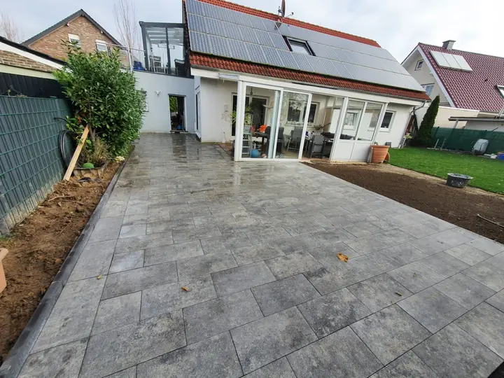 Terrasse aus grauen Platten mit ebenerdigem Übergang zur Rasenfläche