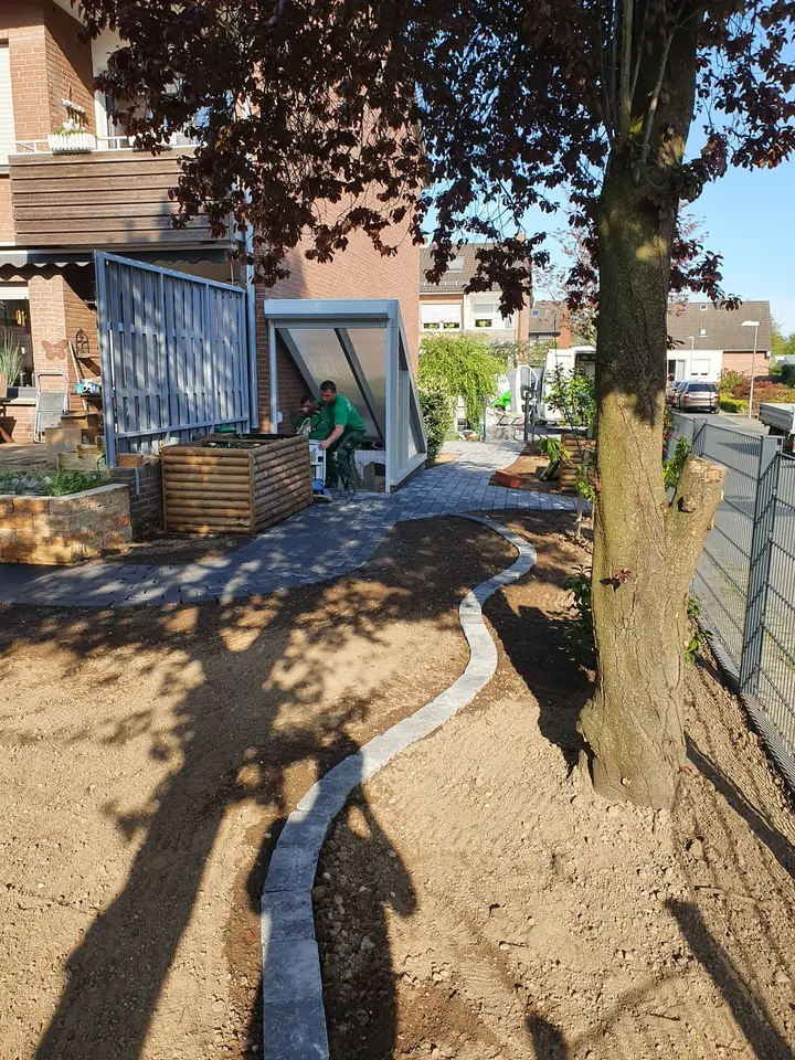 Neu angelegter Pflasterplatz mit schattenspendendem Hausbaum und Sitzbank