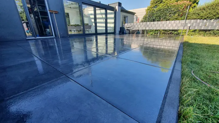 Großzügige Terrassenanlage aus Feinsteinzeug vor einem modernen Glasanbau