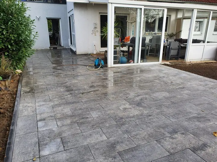 Großformatige Terrassenplatten mit exakter Linienführung vor bodentiefer Glasfront