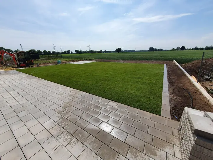 Fertiggestellte Terrassenanlage mit frisch verlegtem, sattgrünem Rollrasen
