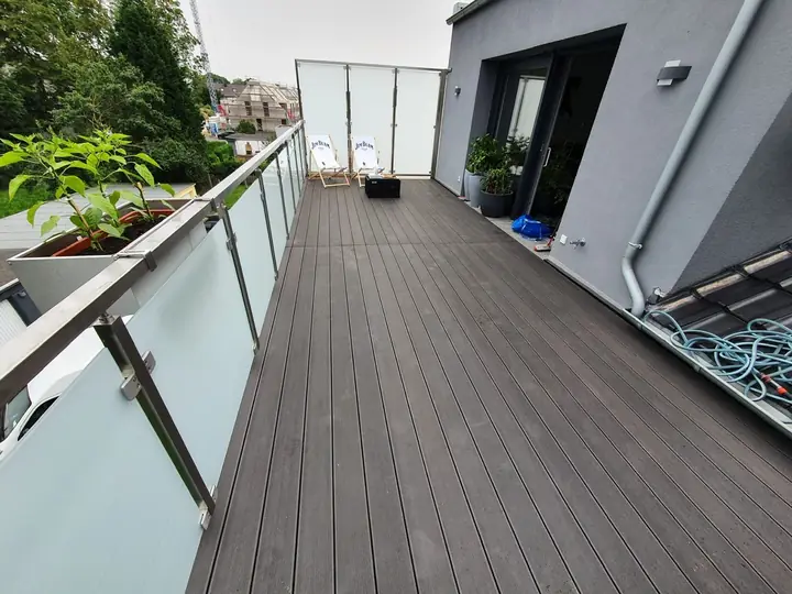 Maßgefertigte Holzterrasse mit Glaselement und harmonischer Bepflanzung