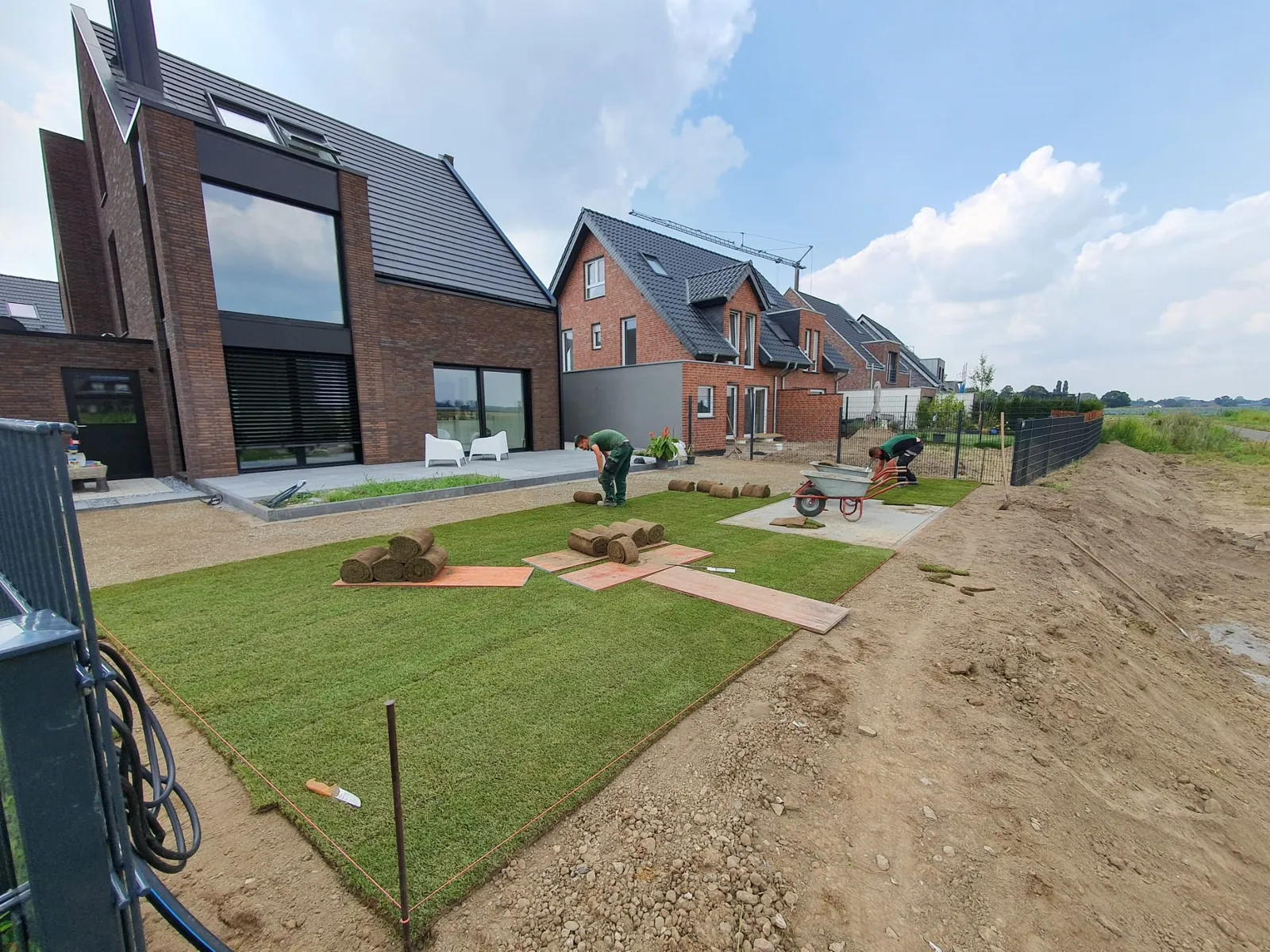 Fachkräfte von Gartenbau Deliu bei der nahtlosen Verlegung von Premium-Rollrasen im Außenbereich